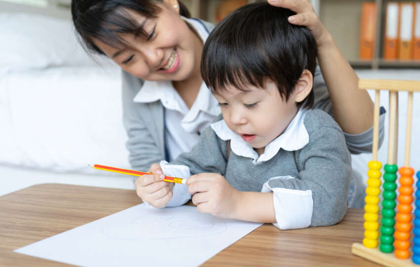 A mother and child are drawing together at a table, seeking comfort and relieving anxiety.