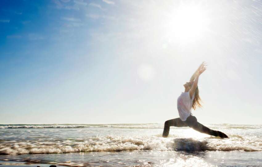 一名女子在海灘上練習瑜伽，在陽光的照耀下，身心同步。