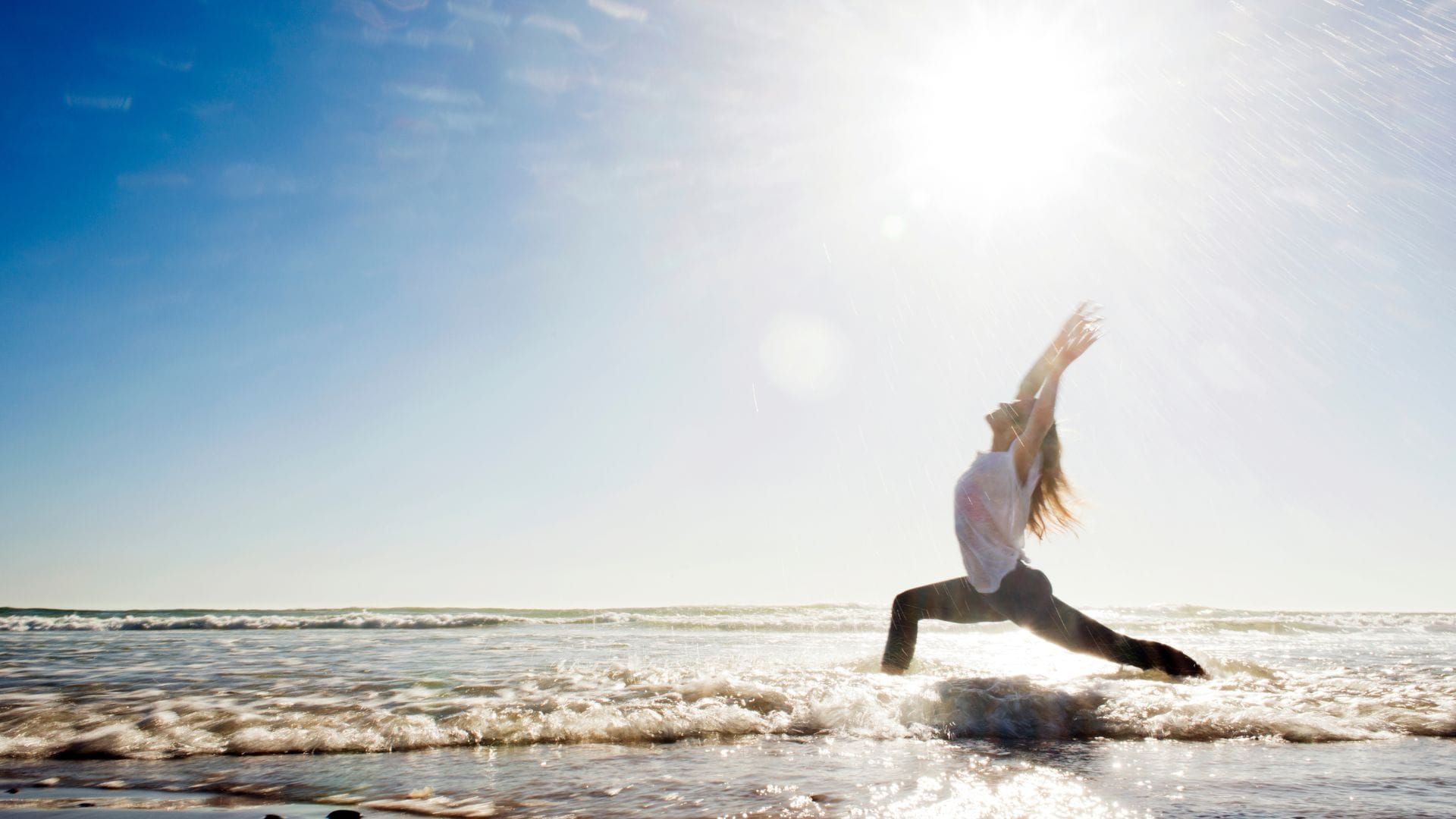 一名女子在海灘上練習瑜伽，在陽光的照耀下，身心同步。
